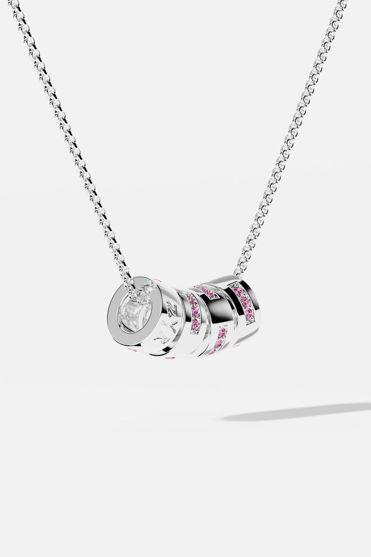 Silver necklace with cylindrical pendant featuring pink and clear stones on a white background