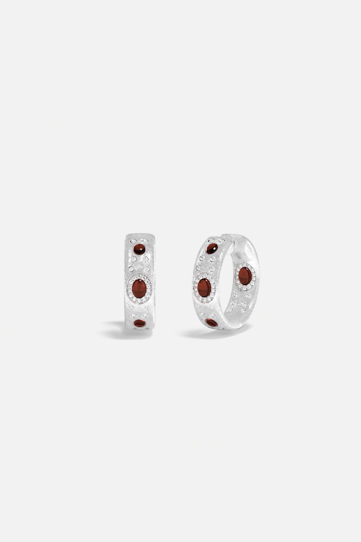APM Hoop Earrings in rhodium finish, deep red accents glowing with quiet elegance.