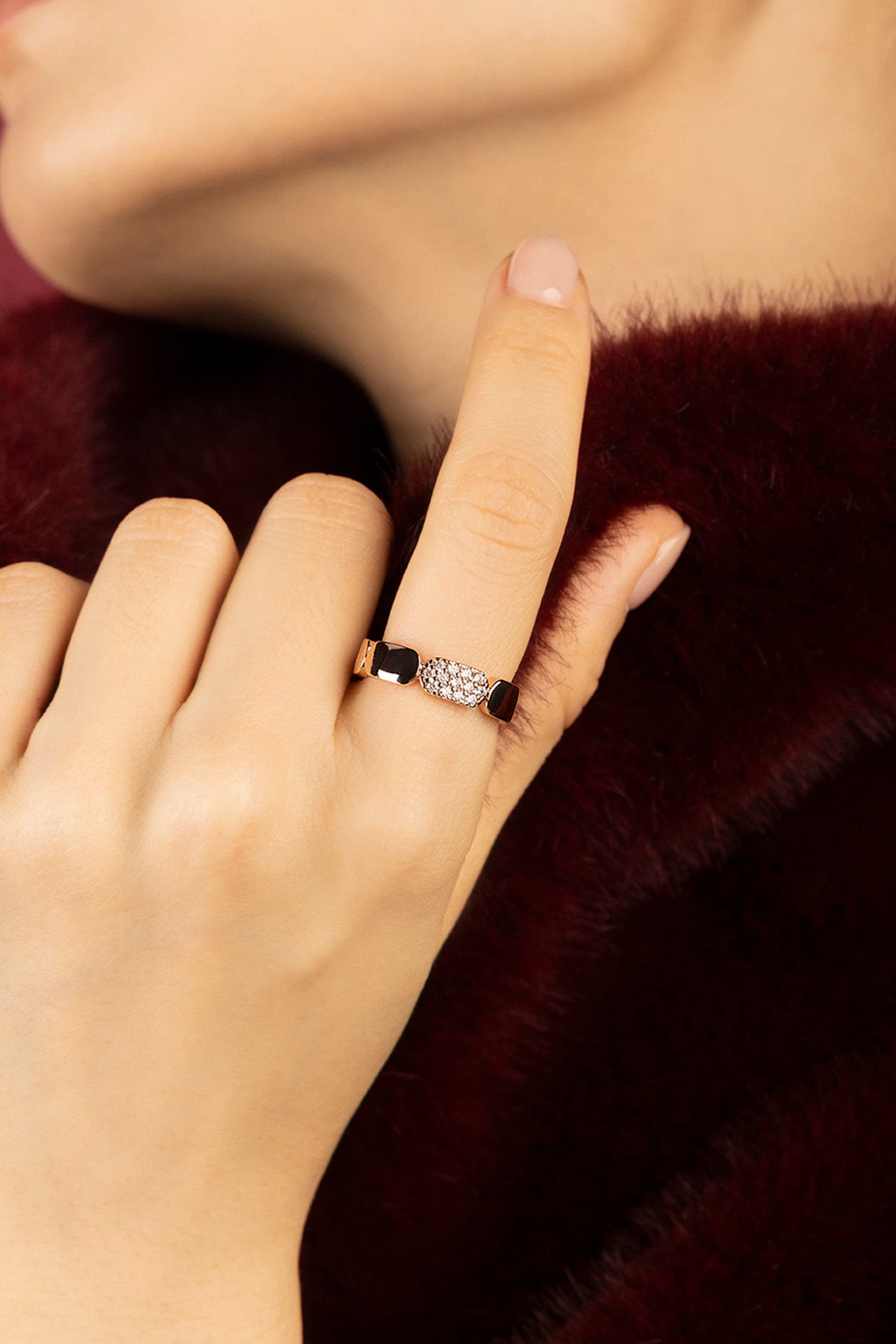 Woman wearing APM Monaco ring, a whisper of noir elegance against burgundy softness.