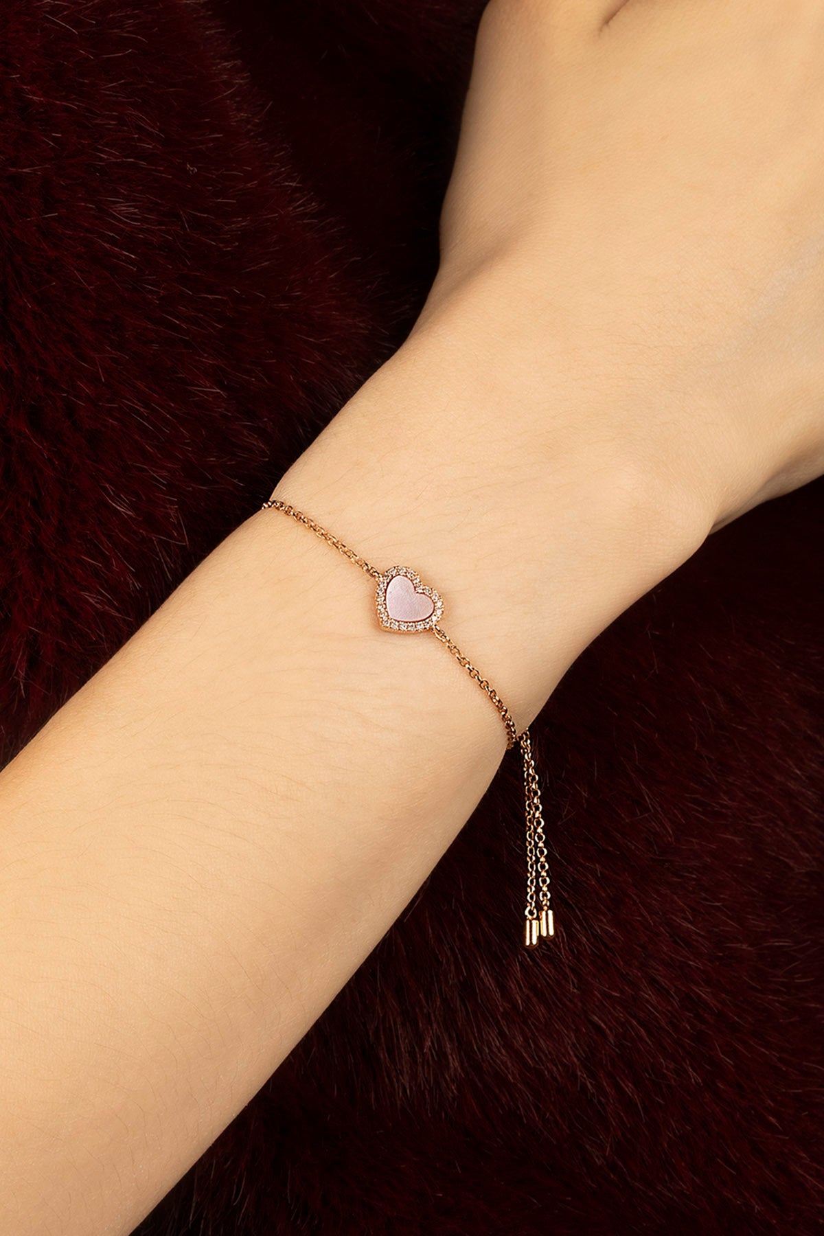 Woman wearing APM heart bracelet, a soft romance whispered in rose.