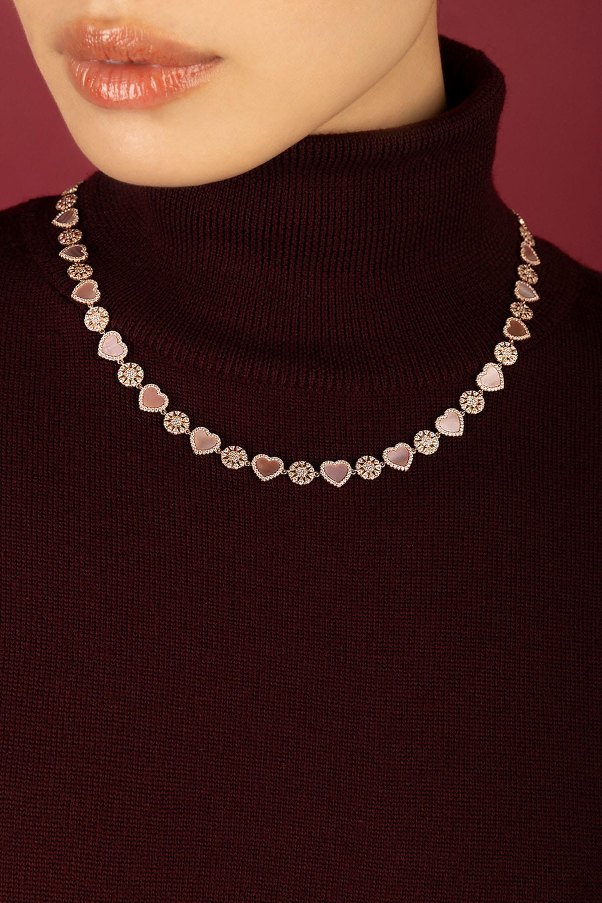 Woman wearing APM necklace, hearts and blooms in soft rosy hues.
