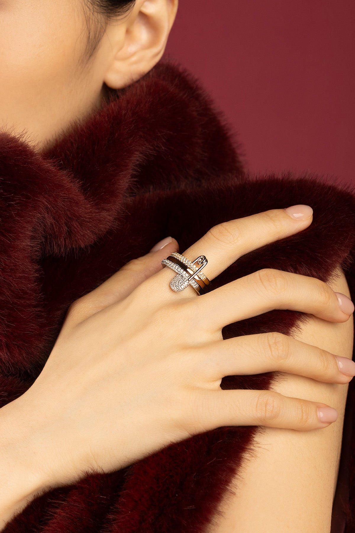 Woman wearing APM ring, a bold shimmer against rich burgundy elegance.