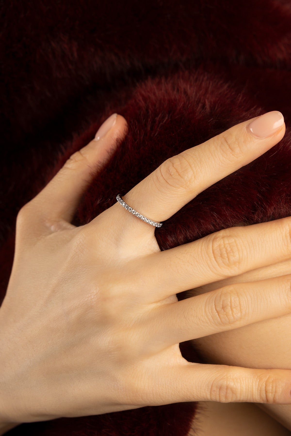 Woman wearing APM ring, a delicate shimmer against velvet warmth.