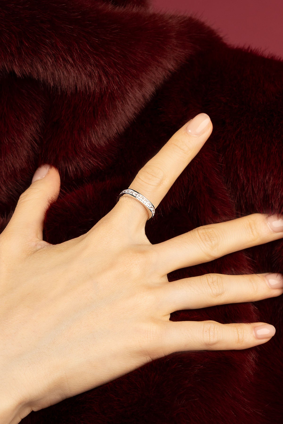 Woman wearing APM Monaco ring, a whisper of shimmer against velvet warmth.