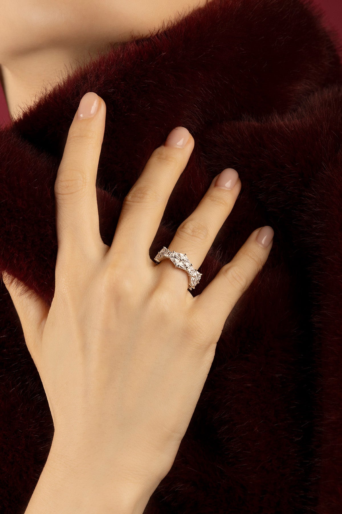 Woman wearing APM ring, a sparkling statement against rich velvet elegance.