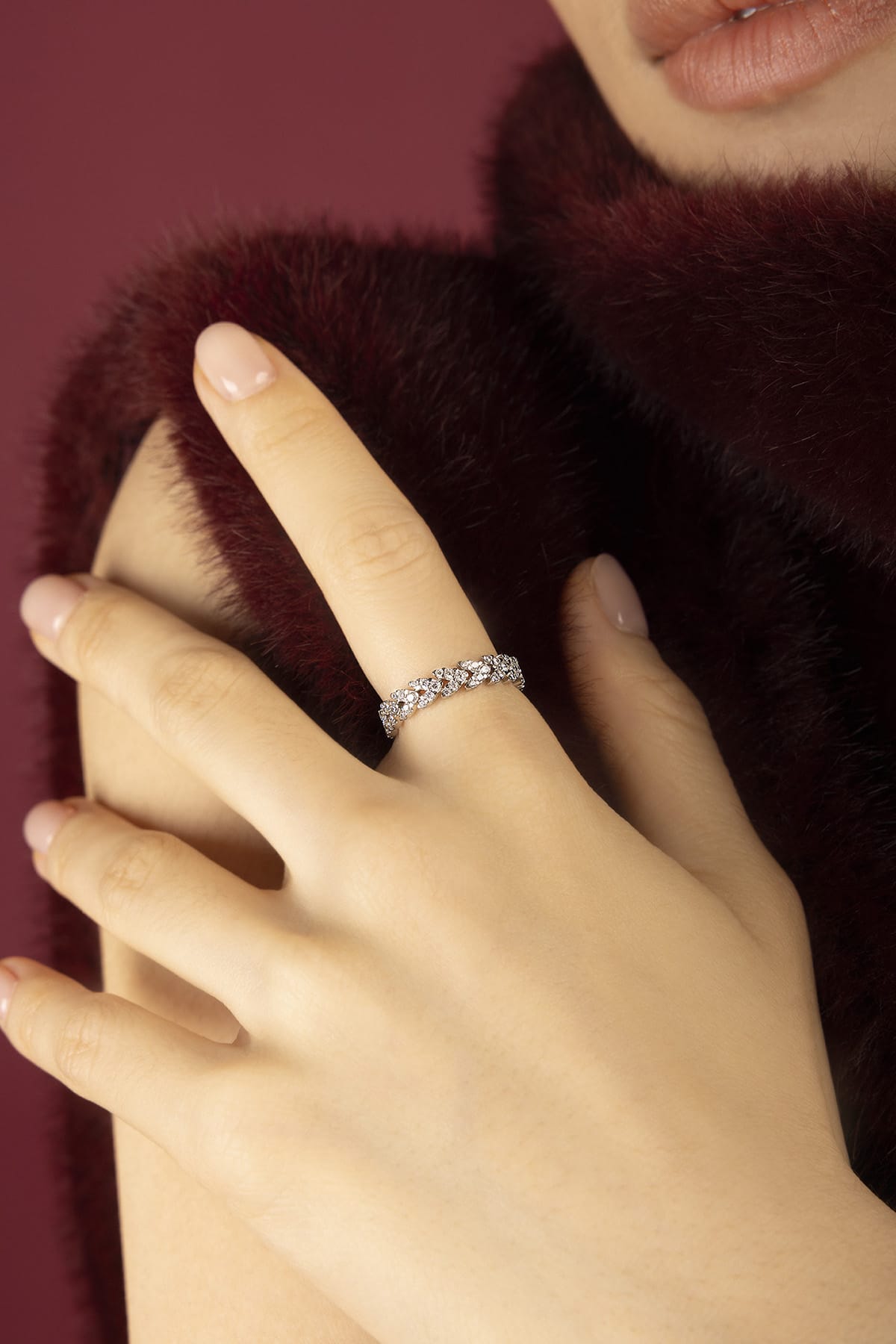 Woman wearing APM Monaco ring, a shimmering whisper against velvet warmth.