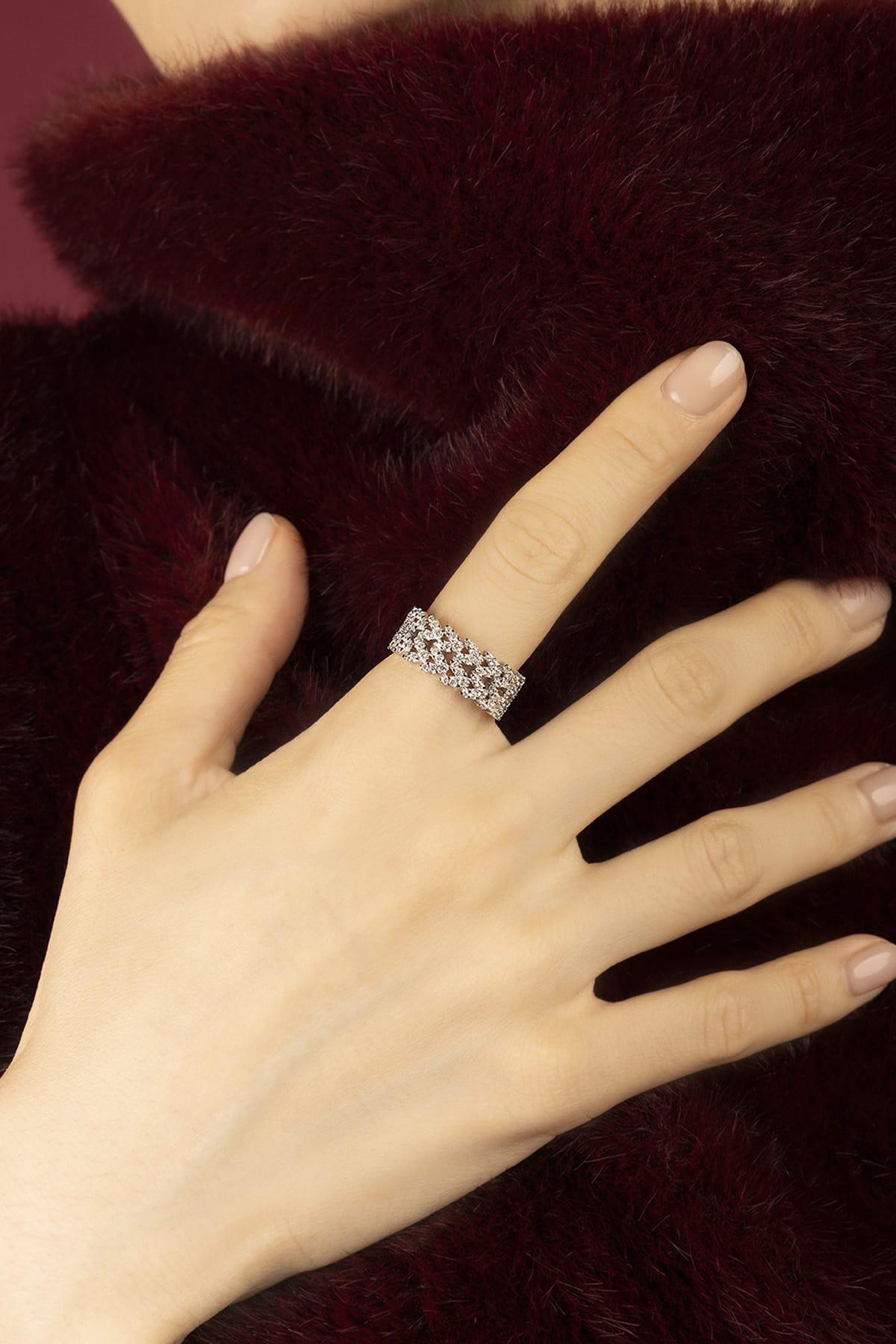 Woman wearing APM ring, a shimmering lace of light against velvet warmth.