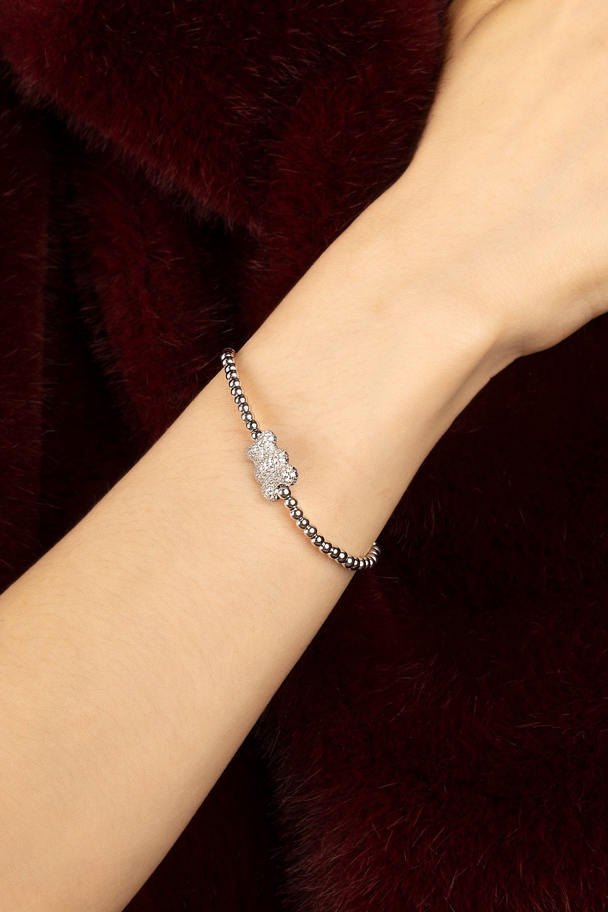 Woman wearing APM beaded bracelet, a playful bear charm shimmering with quiet charm.