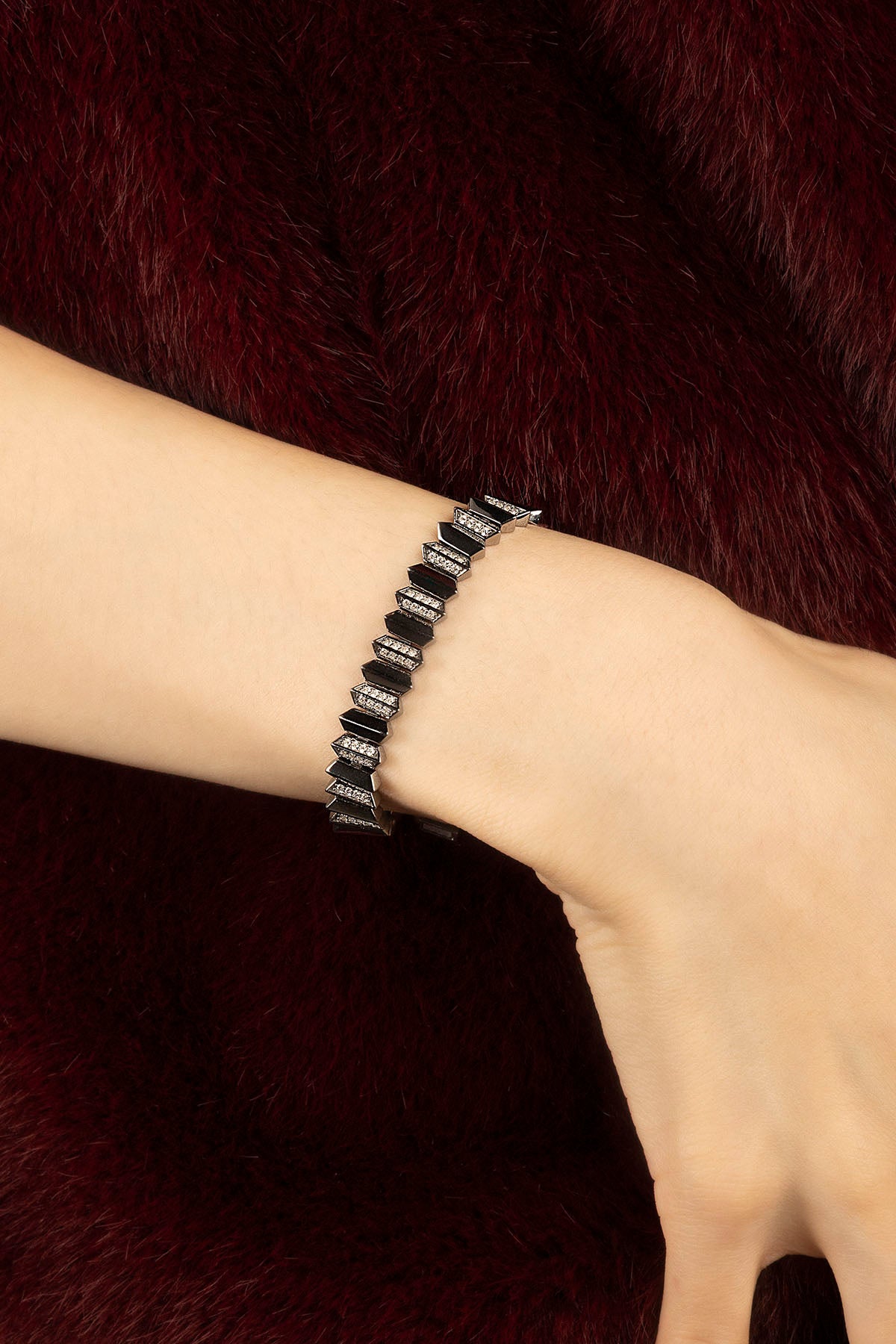 Woman wearing APM Monaco bracelet, bold geometry meets midnight allure.