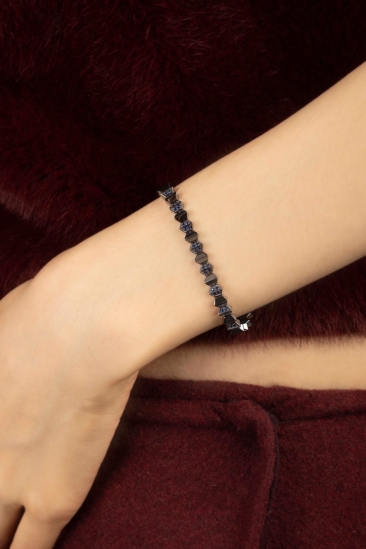 Woman wearing APM Monaco bracelet, a bold edge against soft burgundy.