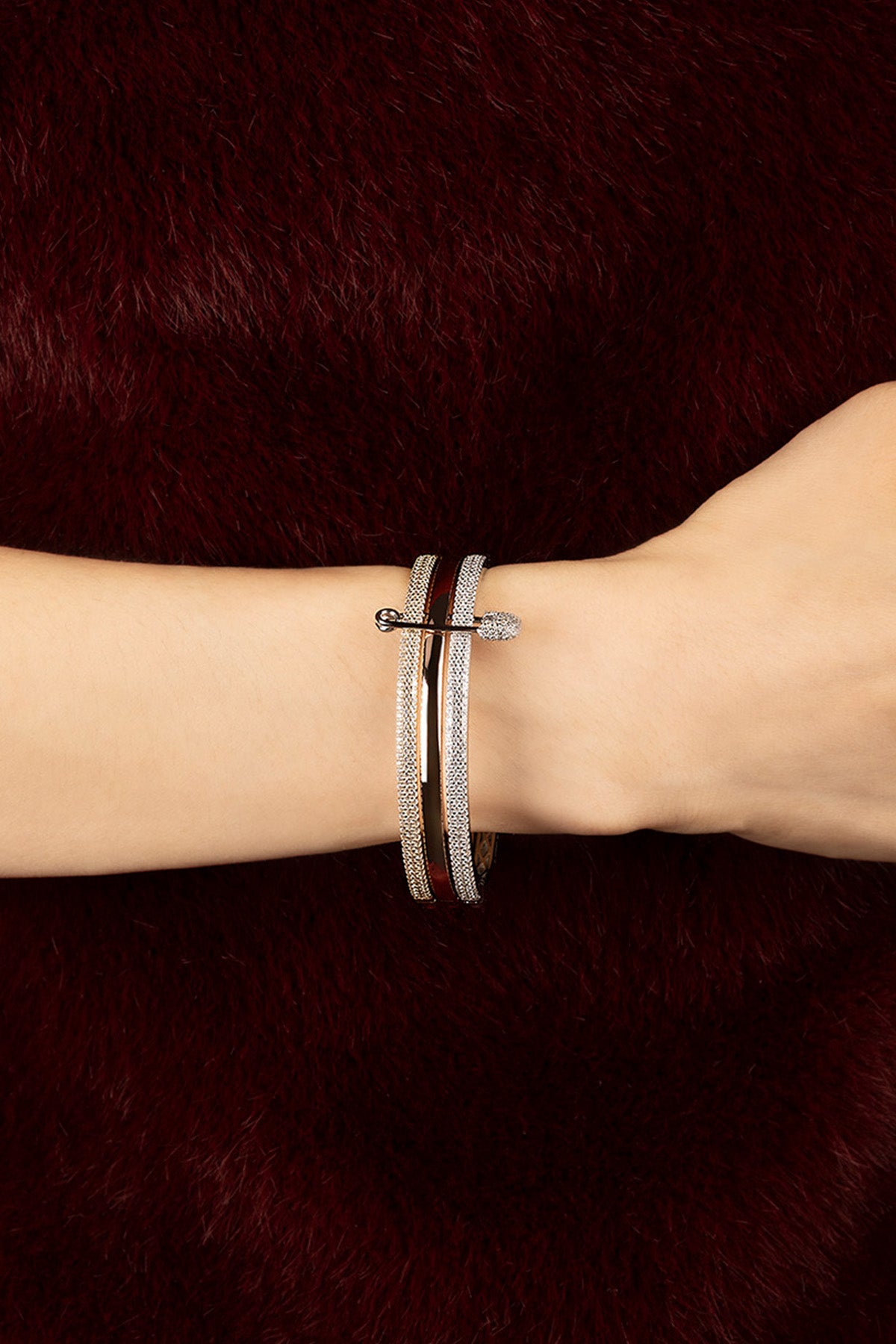 Woman wearing APM Monaco bangle, a whisper of shimmer against deep velvet.