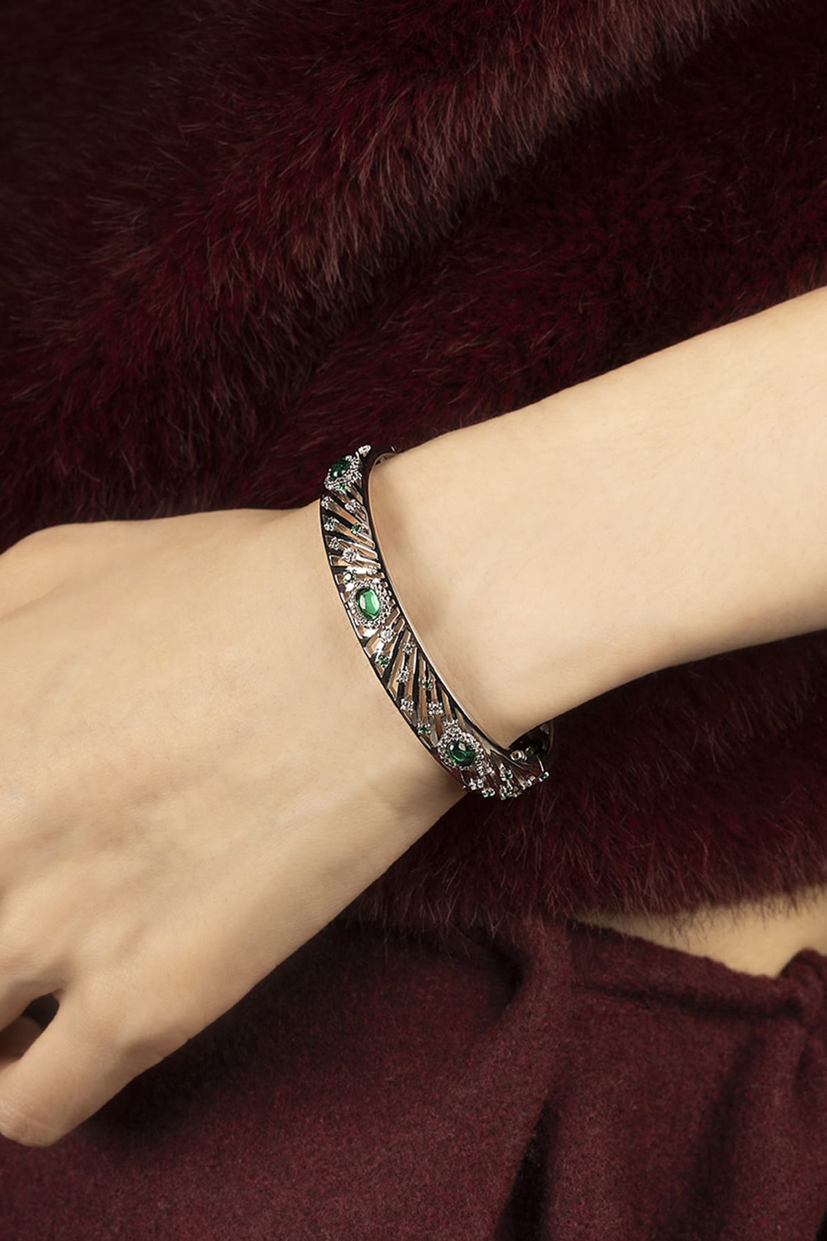 Woman wearing APM bangle, emerald sparkle meets rhodium finish, quiet winter allure.