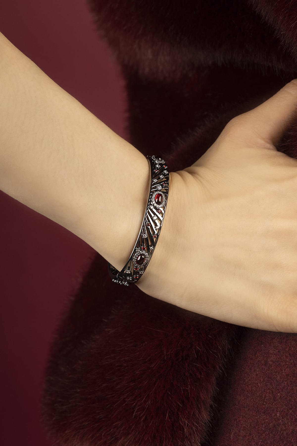 Woman wearing APM Monaco bangle, a bold statement of nocturnal elegance and crimson allure.
