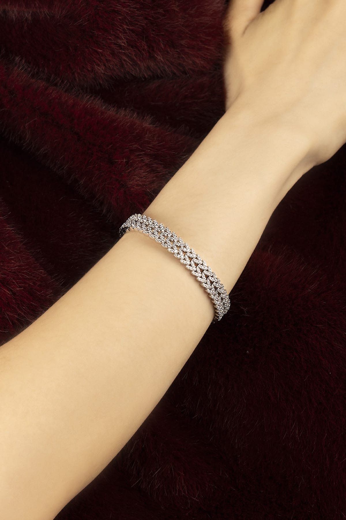 Woman wearing APM bracelet, a shimmering rhodium finish against velvet warmth.