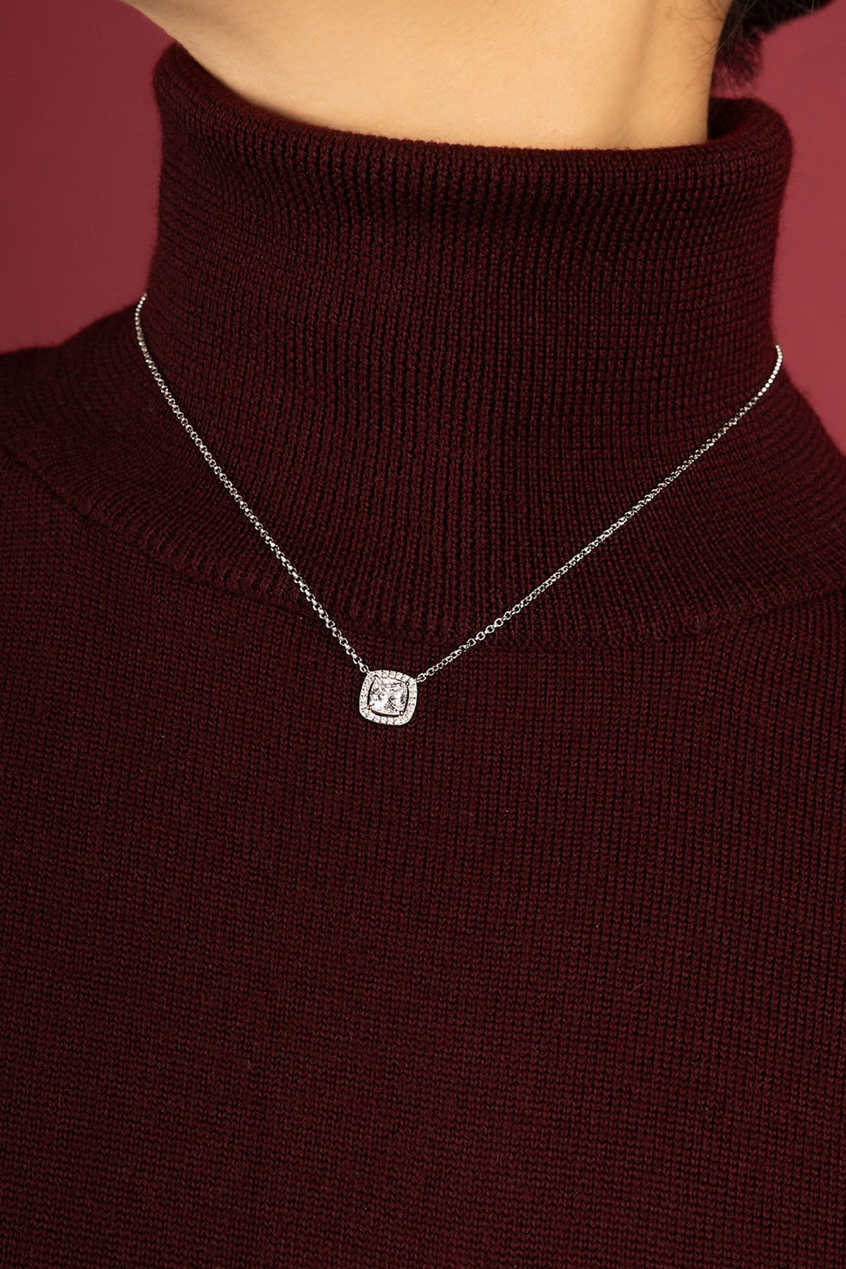 Woman wearing APM Monaco necklace, a luminous accent on cozy burgundy elegance.
