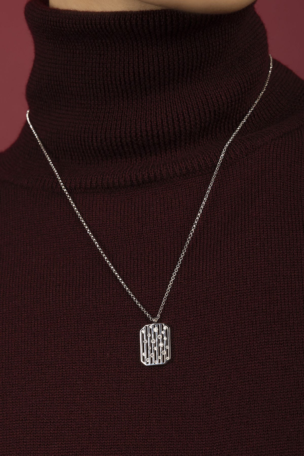 Man wearing APM Monaco pendant necklace, a quiet statement over burgundy knit.