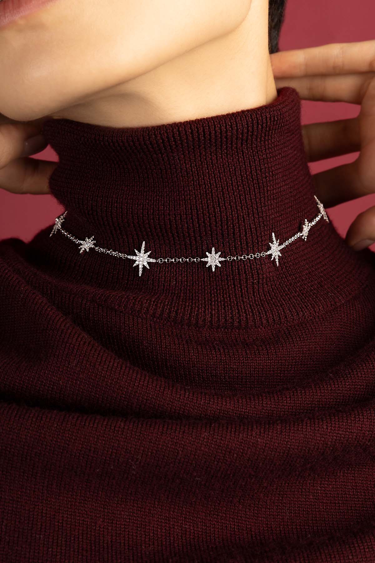 Woman wearing APM Météorites Necklace, a constellation of stars glowing against burgundy.