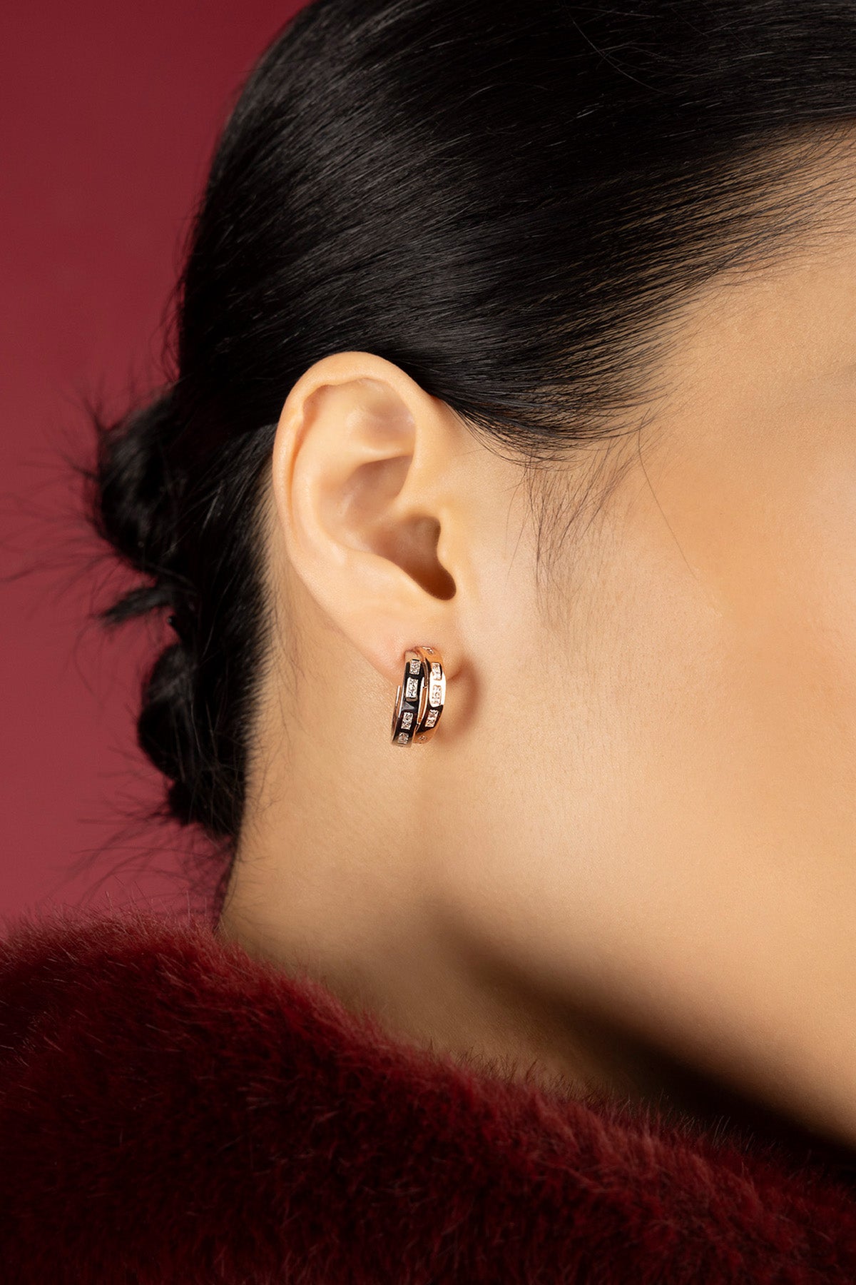 Woman wearing APM hoop earrings, a warm rose glow meets crimson elegance.