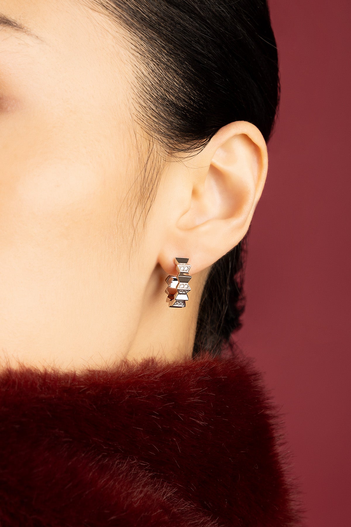 Woman wearing APM geometric hoop earrings, a bold twist on modern elegance.