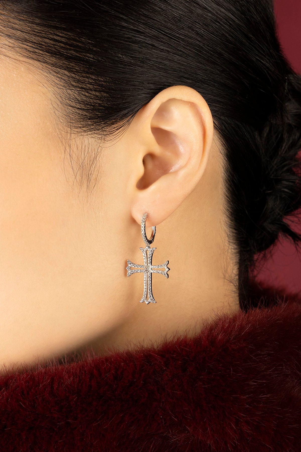 Woman wearing APM cross earrings, a whisper of gothic romance meets modern elegance.