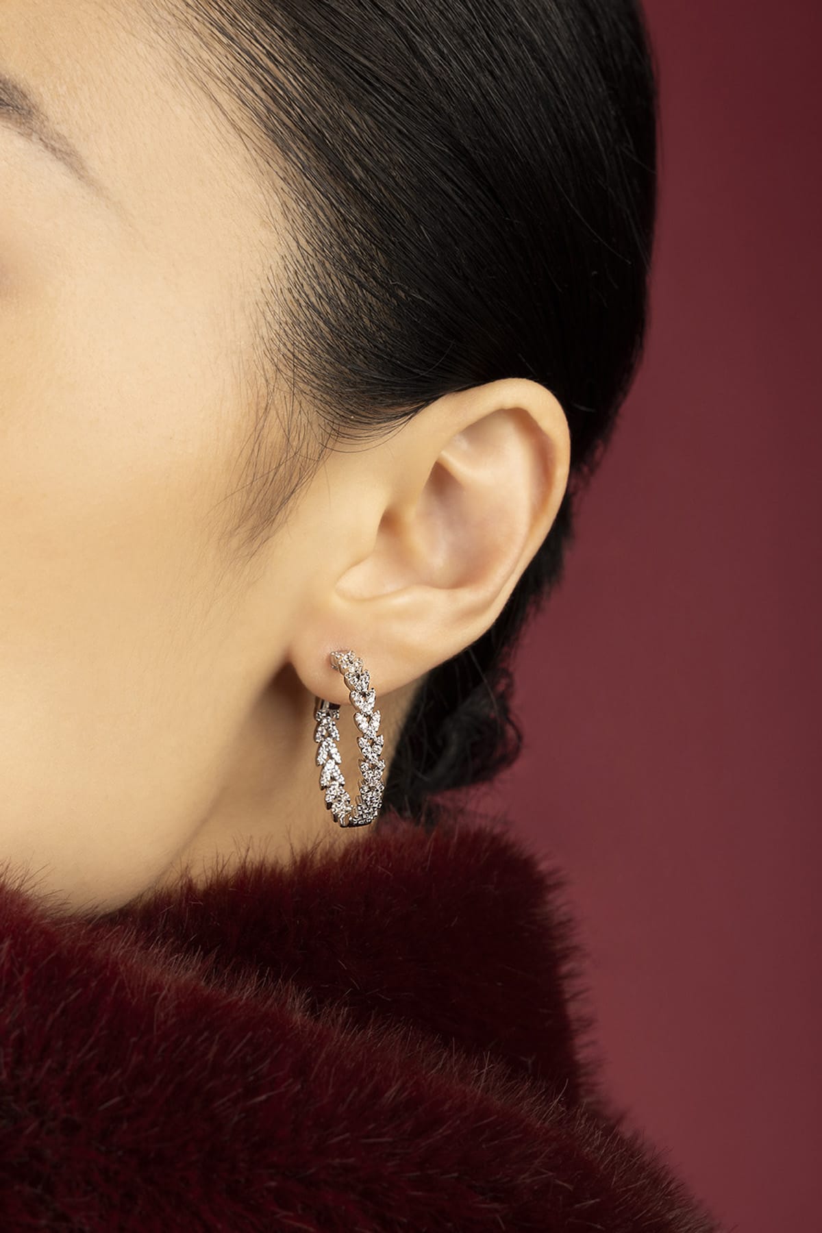 Woman wearing APM hoop earrings, a shimmering whisper of understated glamour.