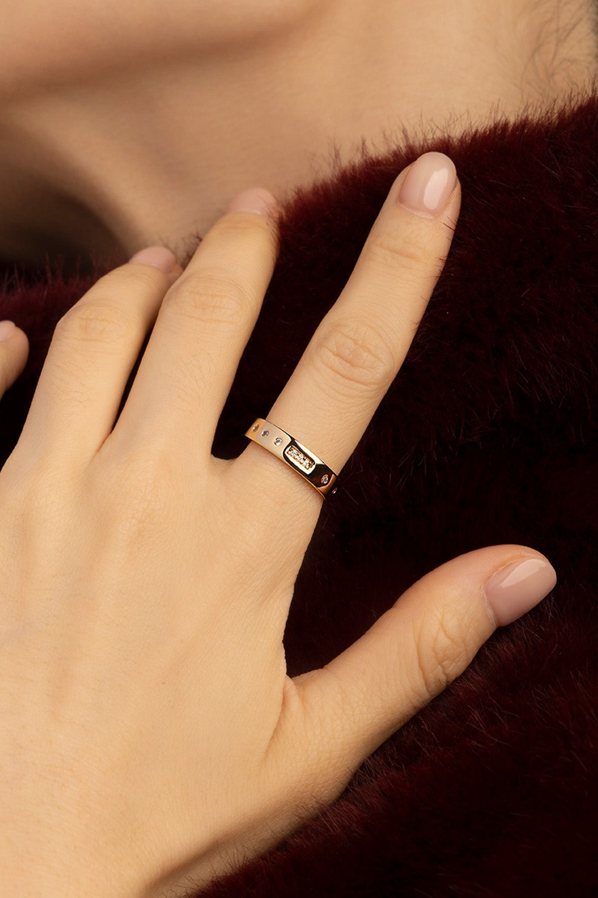 Woman wearing APM Morse Ring, a whisper of golden elegance against soft warmth.