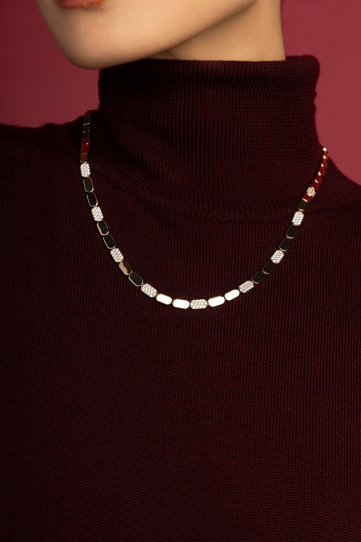Woman wearing APM necklace, a quiet sparkle against deep burgundy.