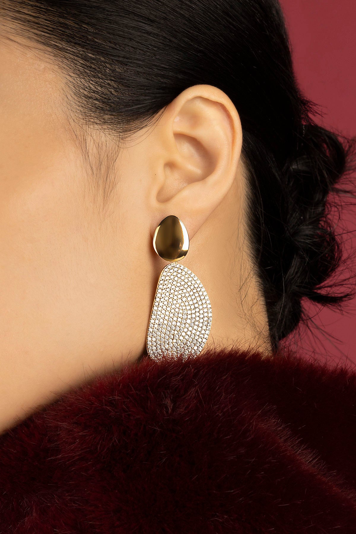 Woman wearing APM Monaco earrings, a golden statement of quiet evening allure.