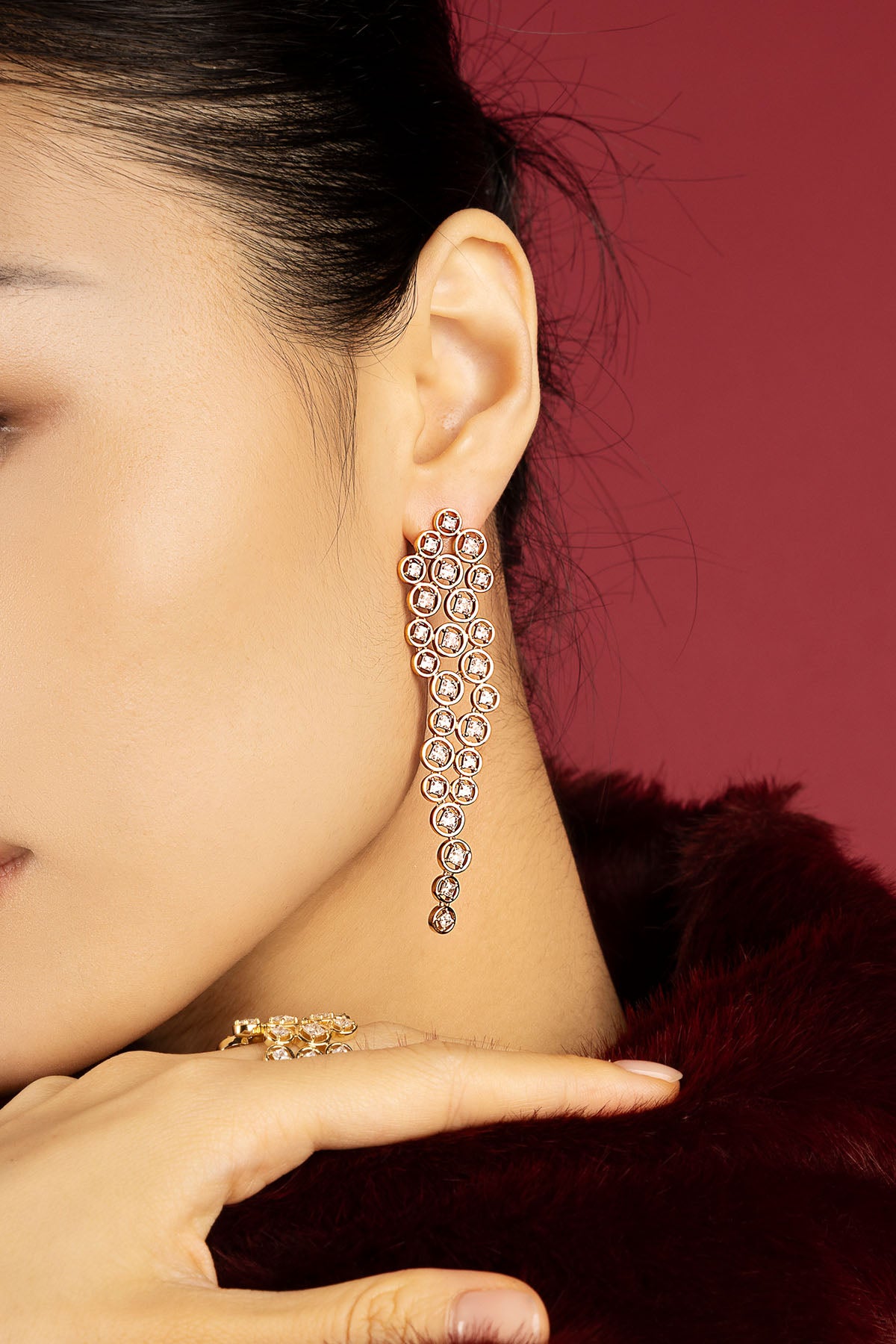 Woman wearing APM cascading earrings, a shimmering cascade of golden allure.