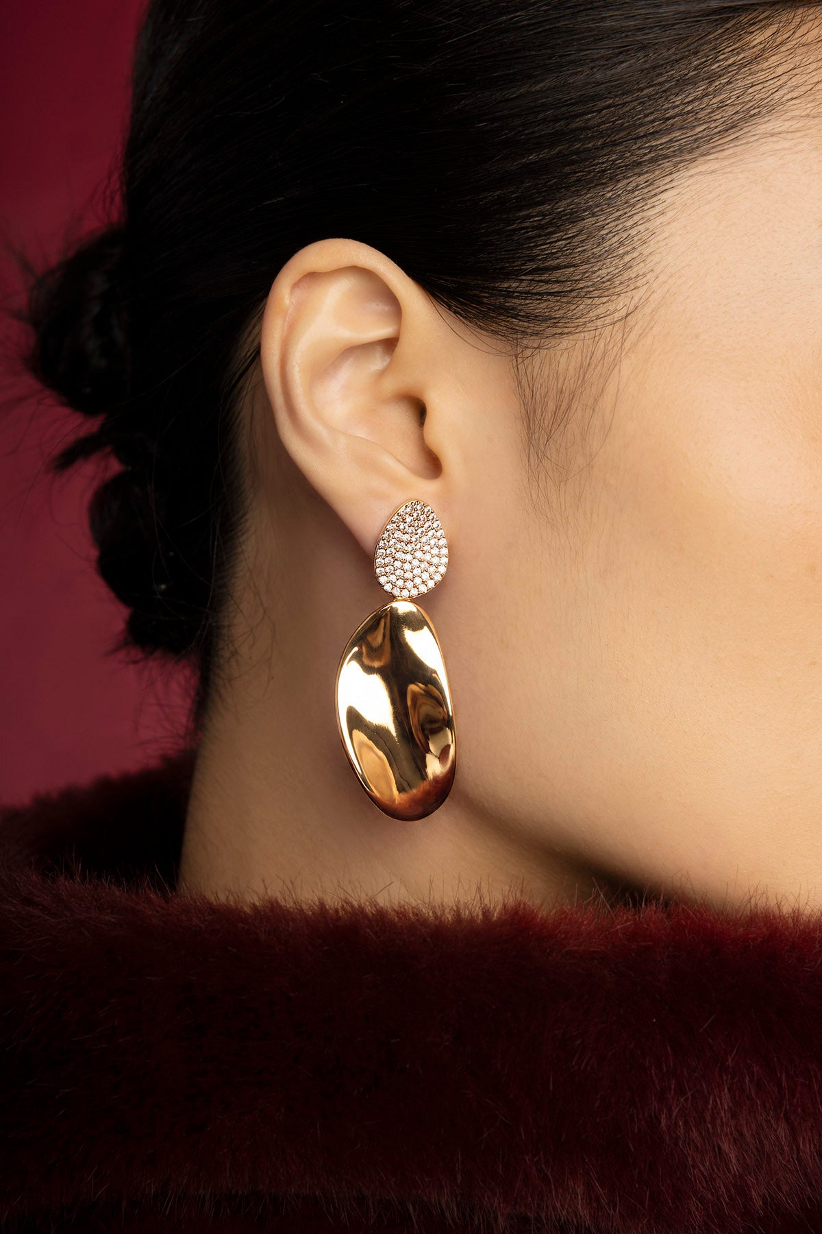 Woman wearing APM drop earrings, a golden glow of quiet elegance.