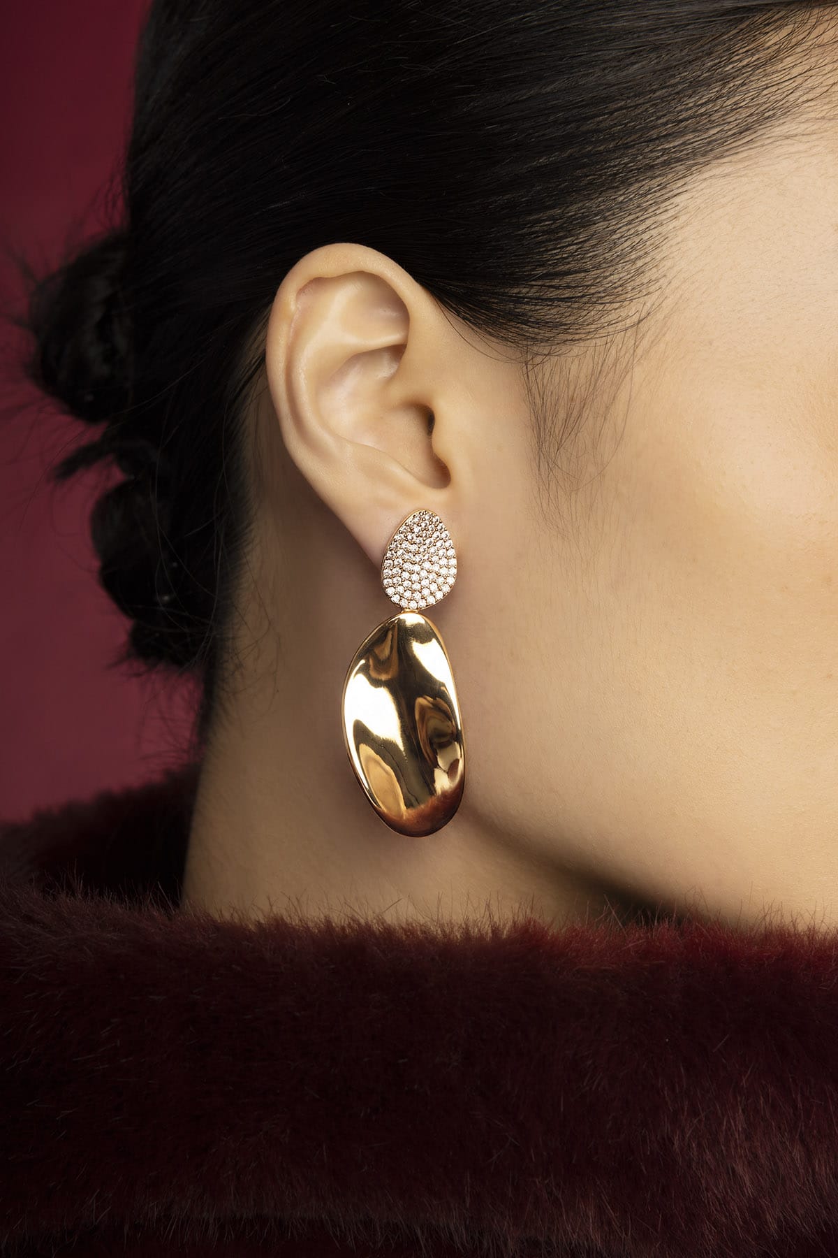 Woman wearing APM drop earrings, a golden glow of quiet elegance.