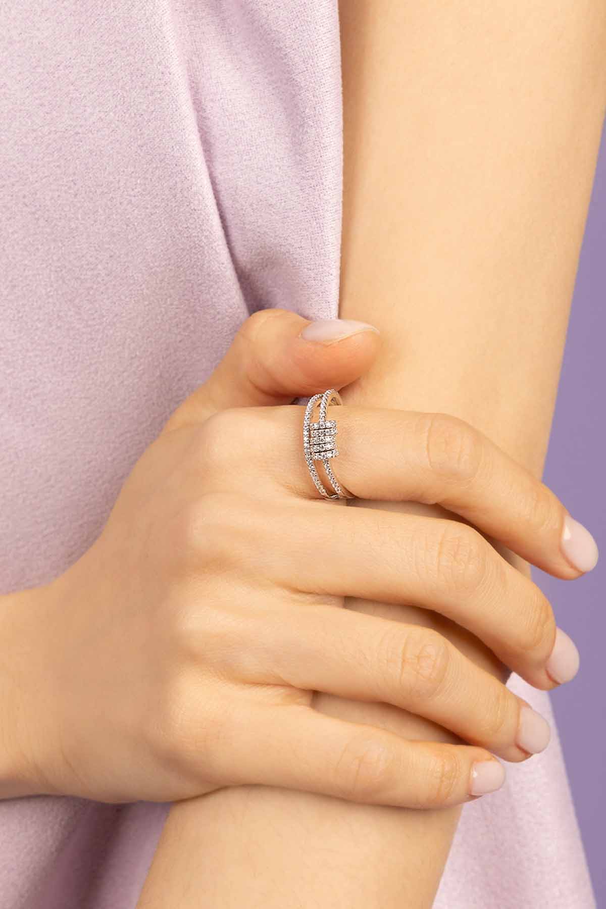 Close-up of a hand wearing APM MONACO double ring with sliding hoops in silver on a light purple background