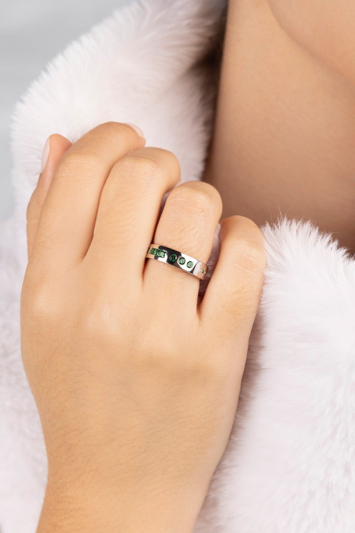 Hand wearing a ring on a white fur background