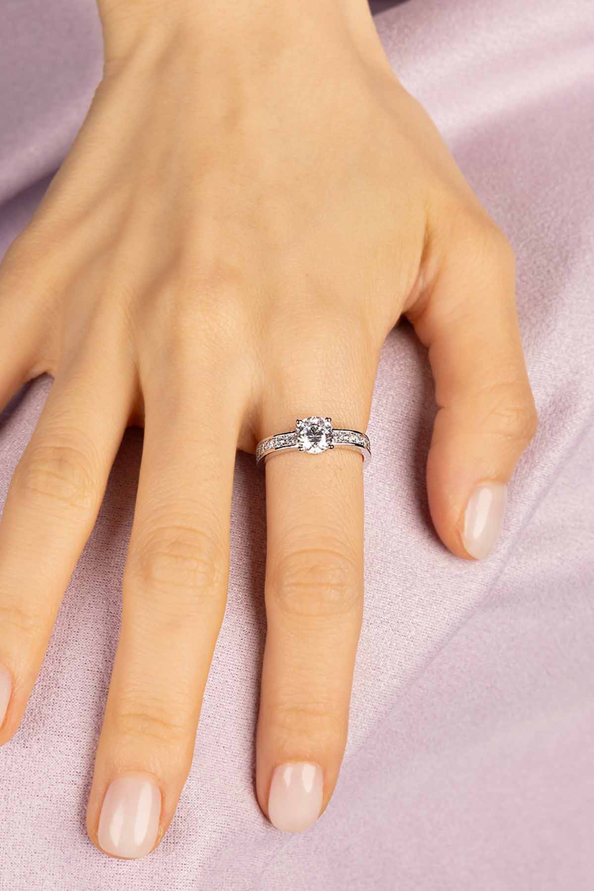 Silver ring on a person's finger against a pink background