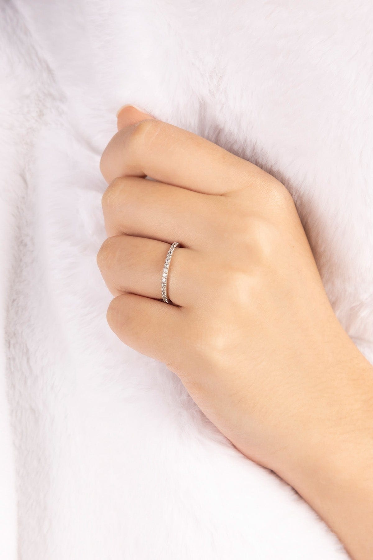 Hand wearing APM MONACO silver ring with linear pave design on a white background