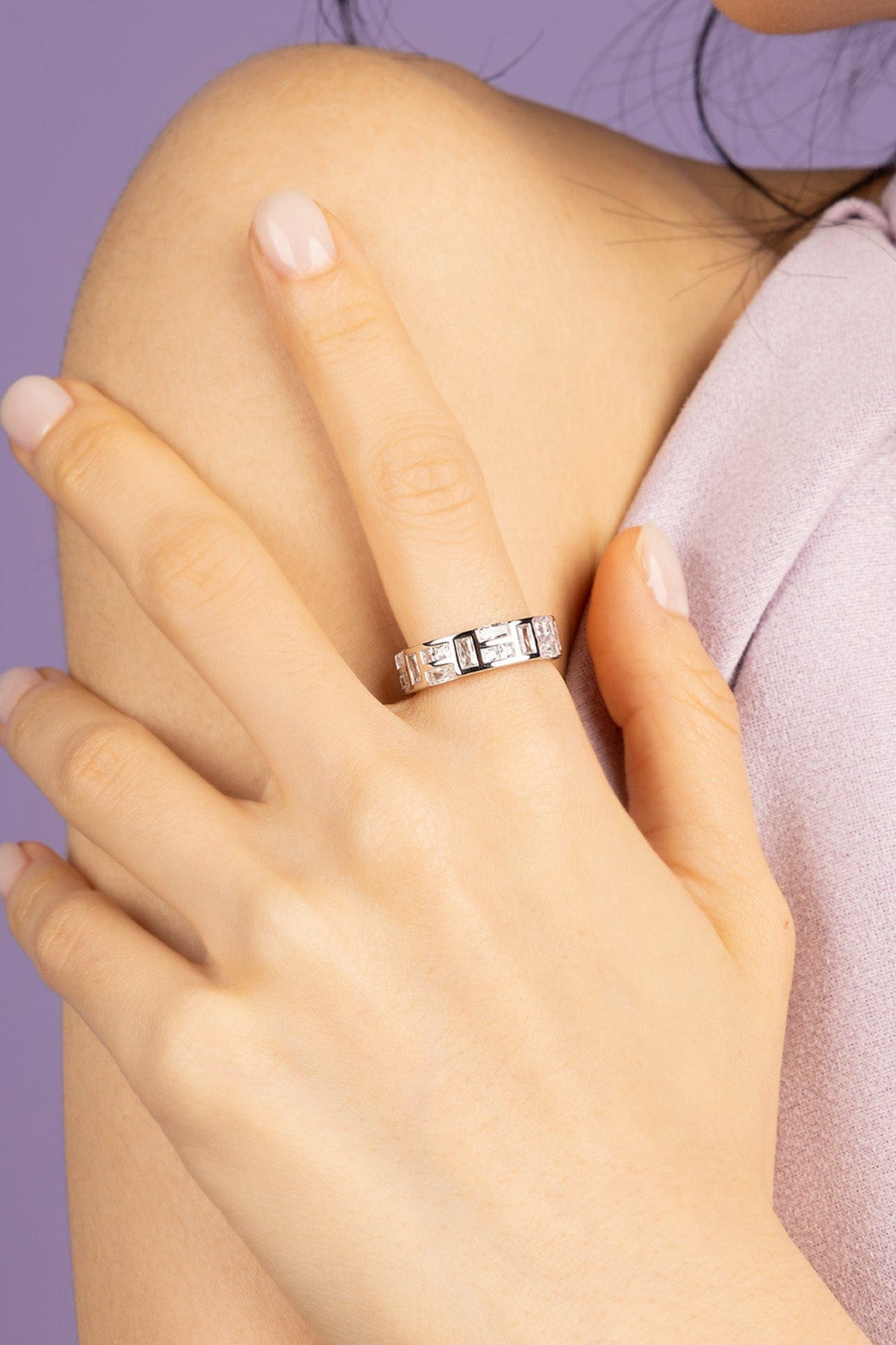Hand wearing APM MONACO ice Silver-tone ring on a purple background