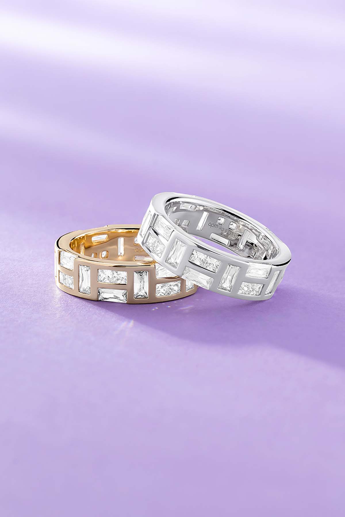 Two APM MONACO ice rings on a purple background, one is yellow god one is Silver-tone