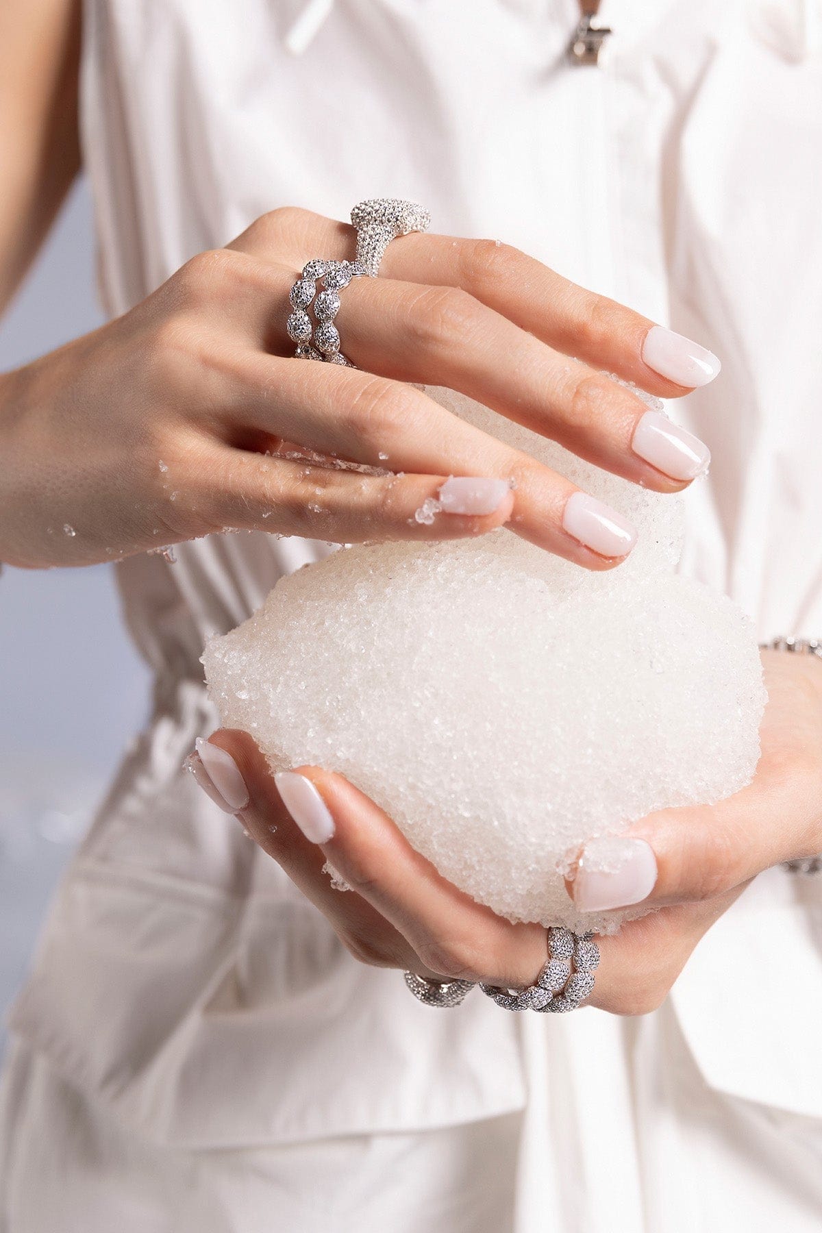 Close-up of hands holding a snow ball with APM MONACO pave rings on fingers 