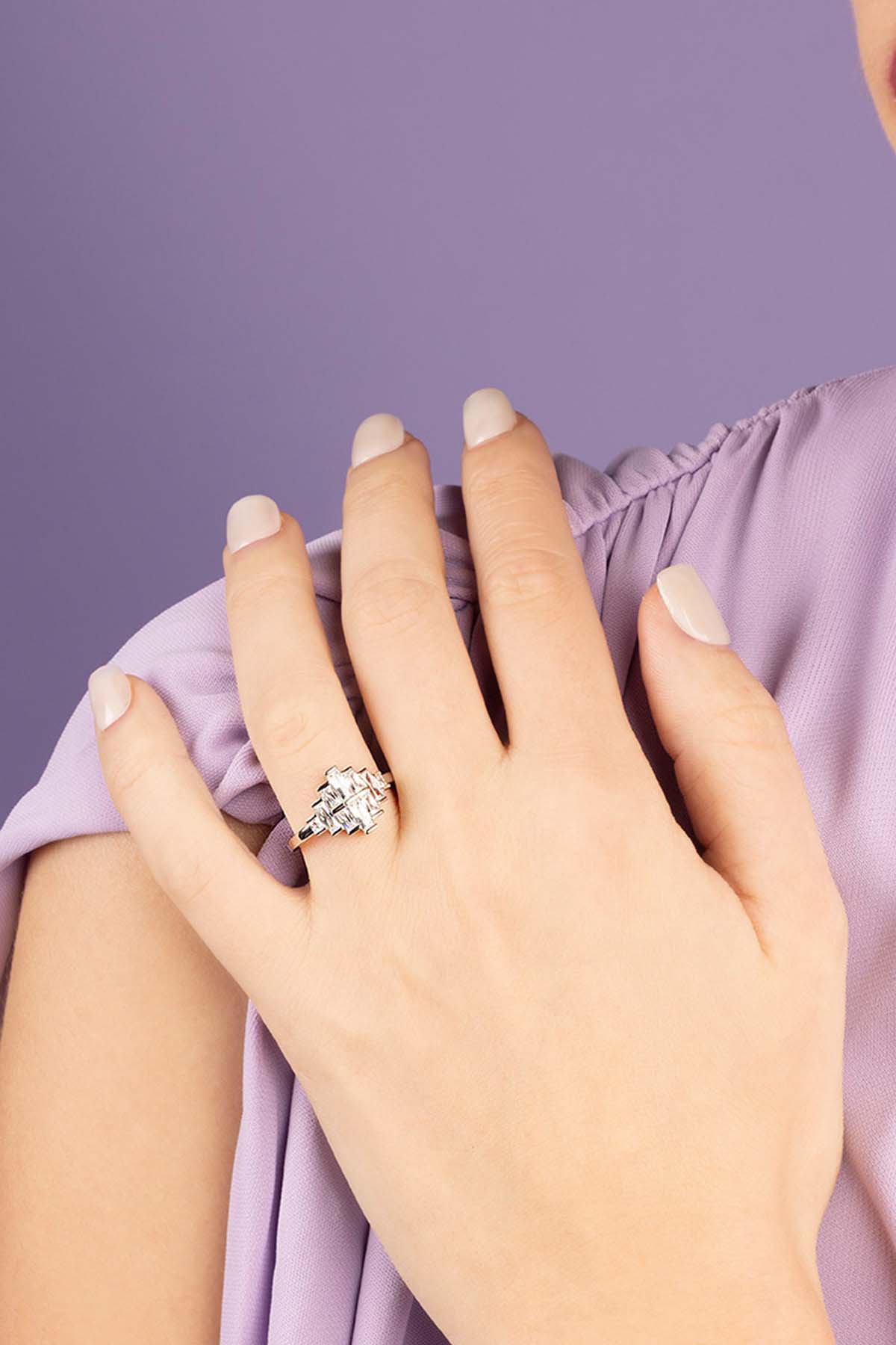 Hand wearing a zirconia ring with a purple background
