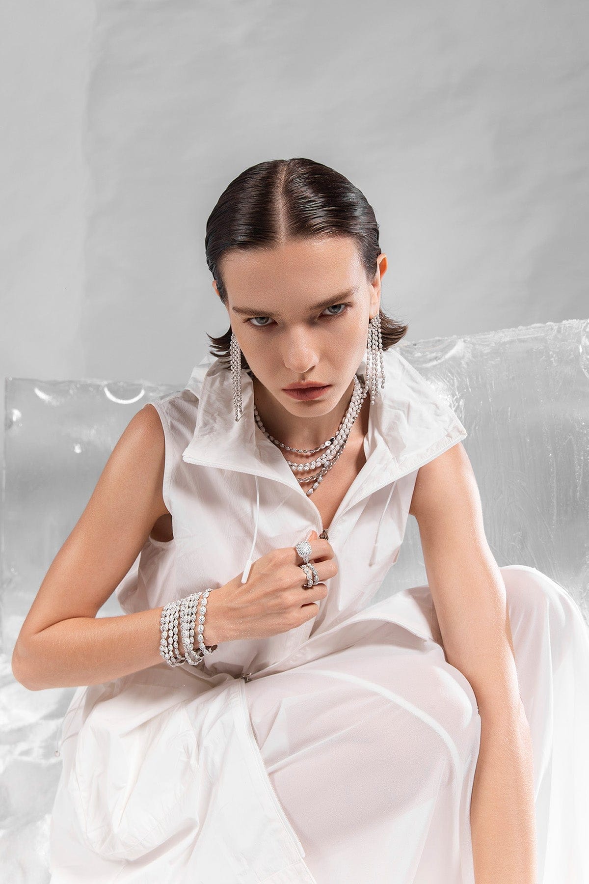 Woman in a white dress with APM MONACO jewelry on a gray background