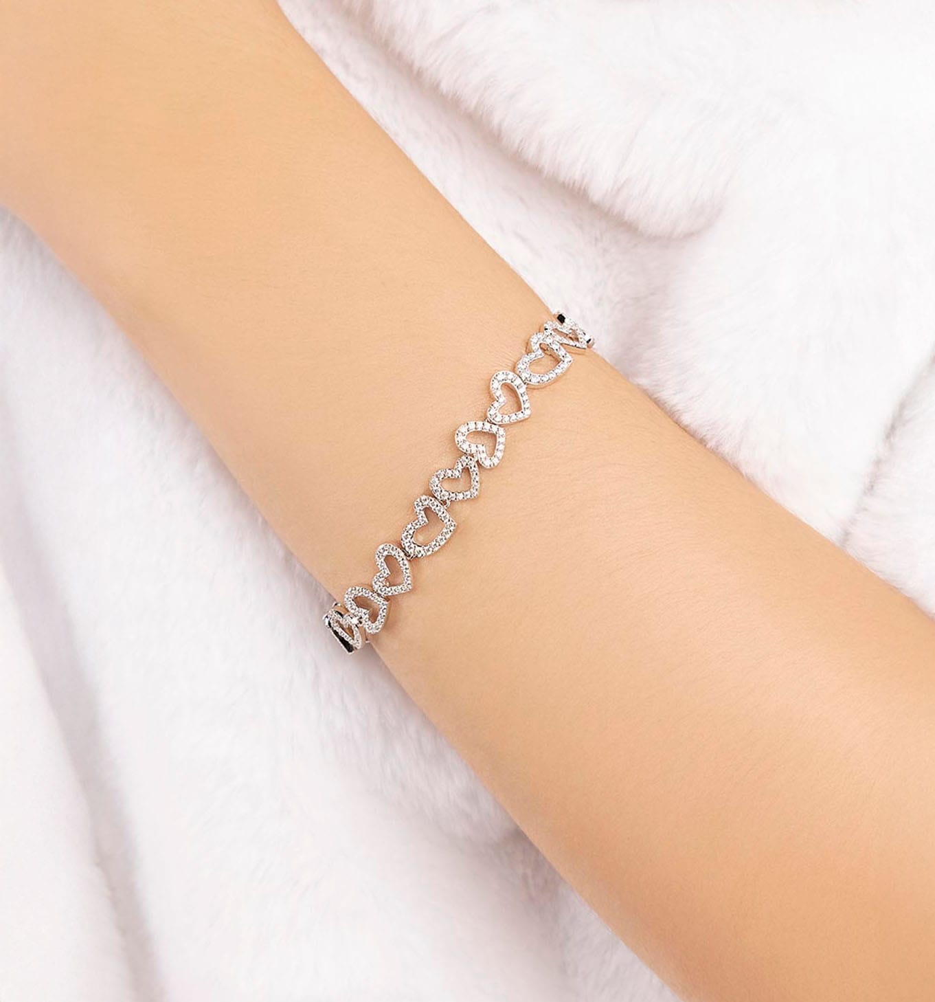 APM MONACO silver bracelet with heart designs on a person's wrist against a white background