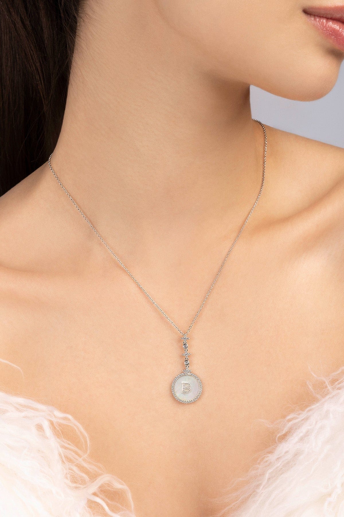Necklace with a pendant featuring the letter "B" and adorned with white nacre worn by a model