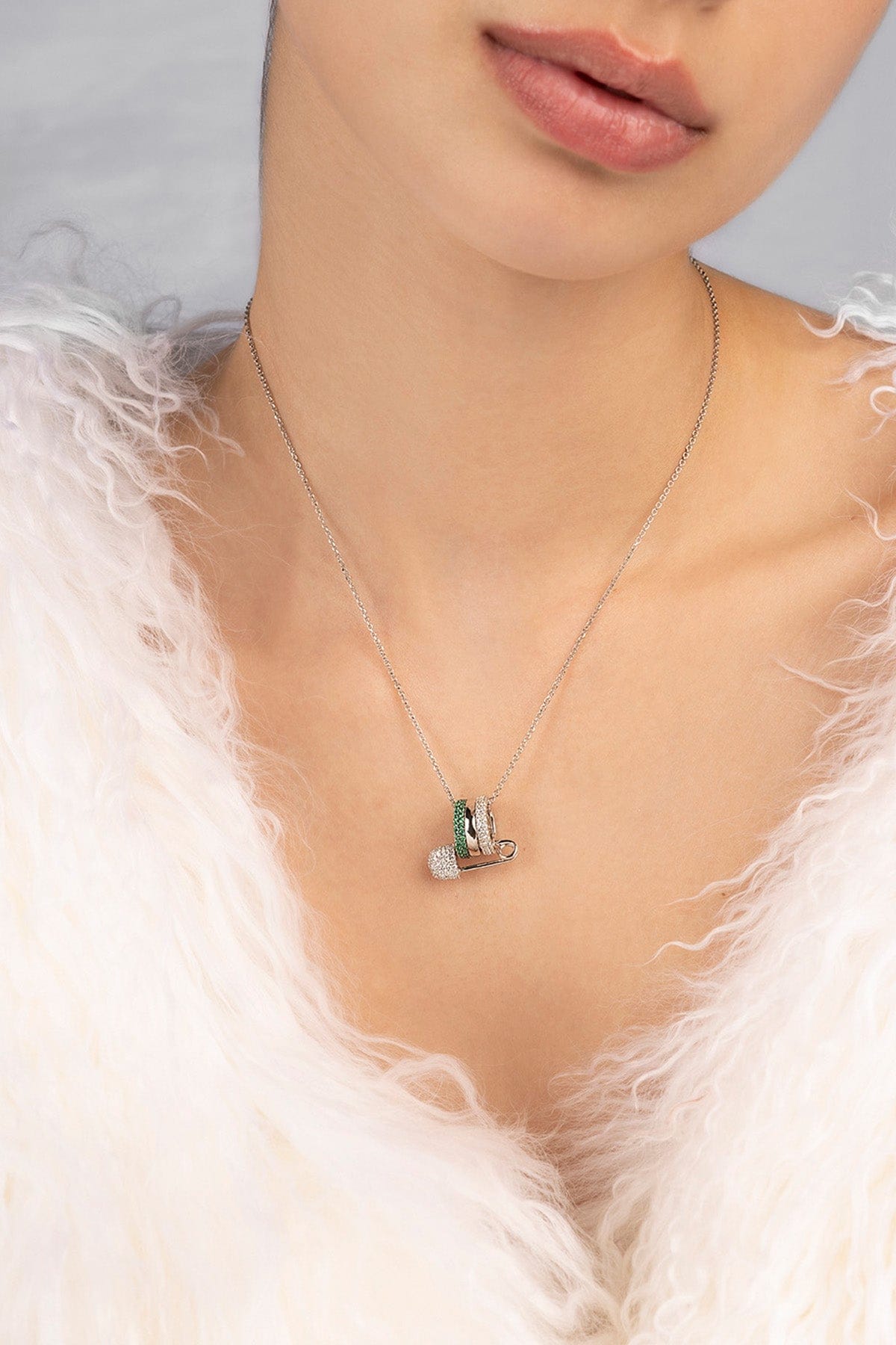Necklace with a small green pendant worn by a person against a neutral background