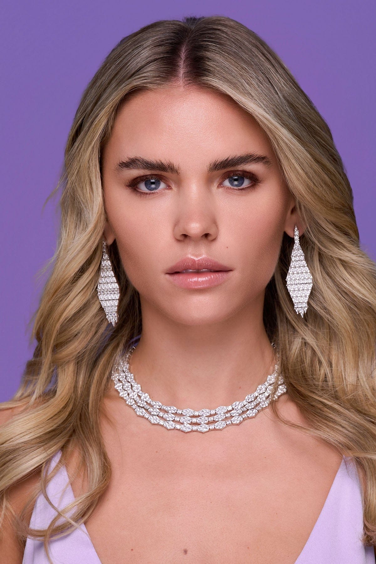 a person wearing the drop earrings on a purple background