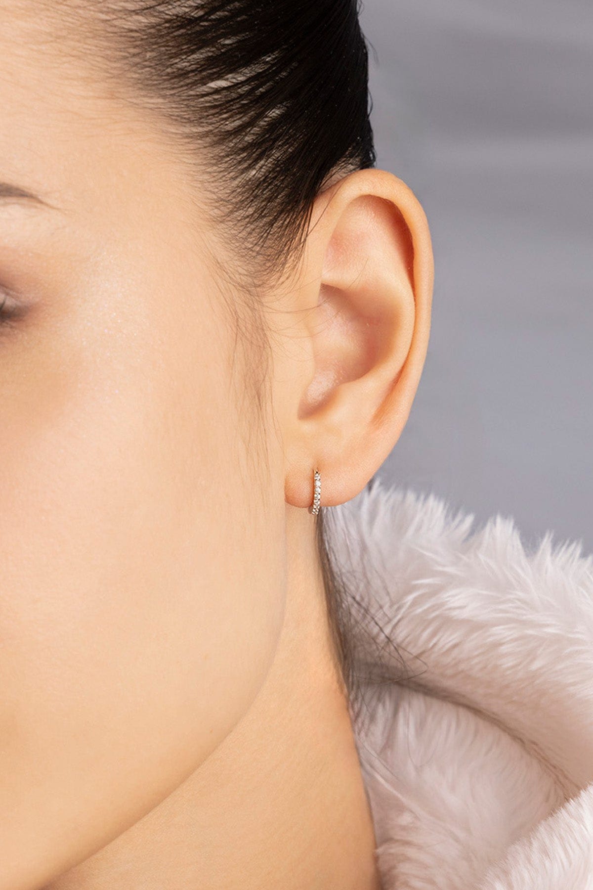 Close-up of an ear wearing APM MONACO silver earring with 6mm paved hoop design 