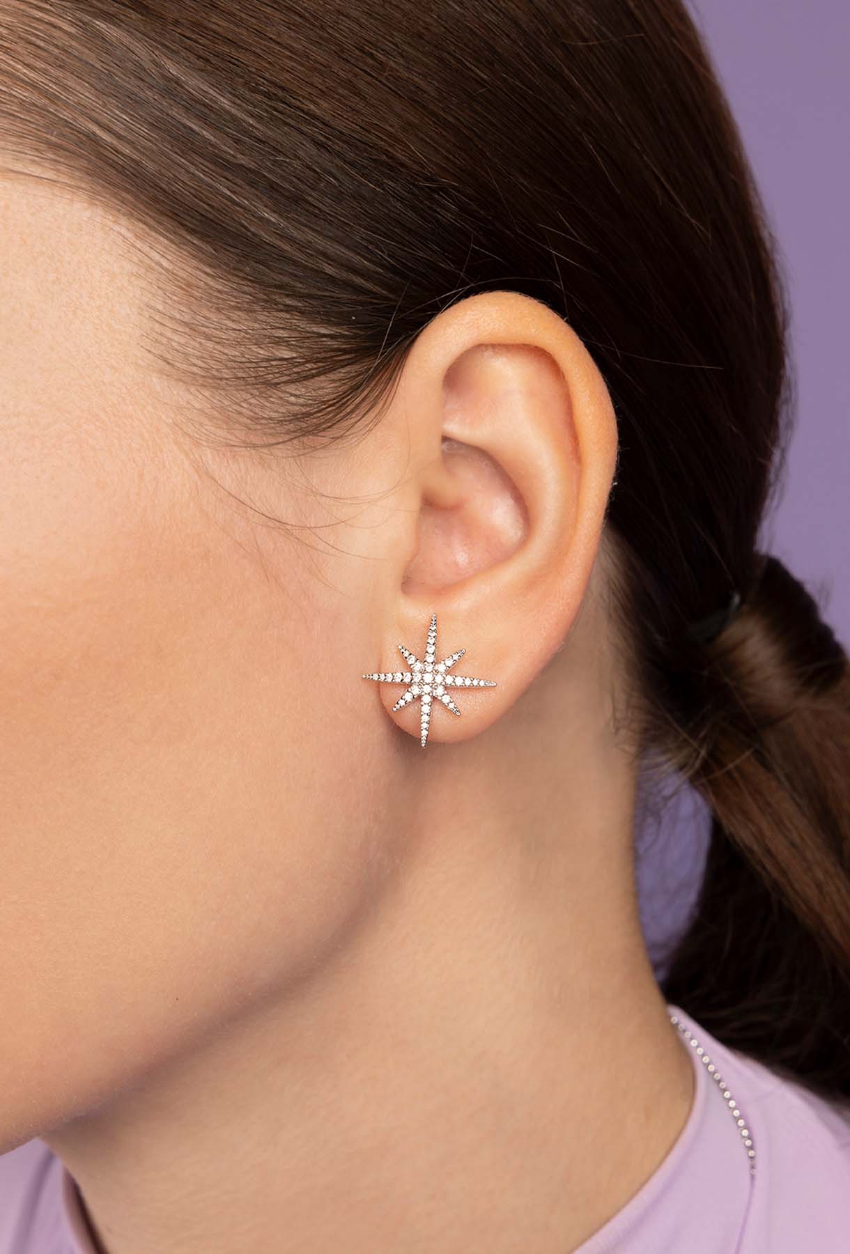 Close-up of an ear wearing a star-shaped earring with a blurred background