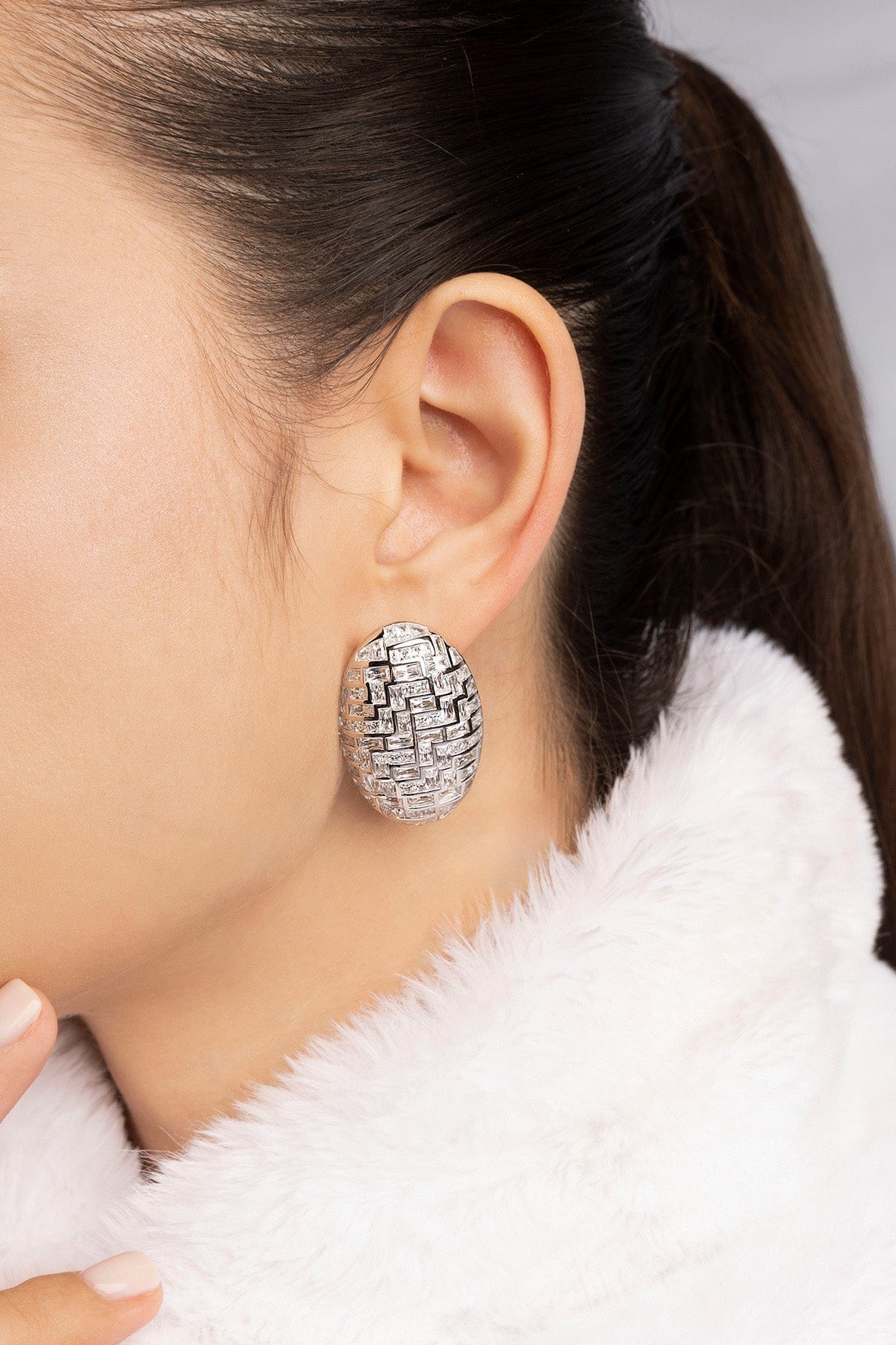 Close-up of a model wearing a silver statement earring with a blurred background