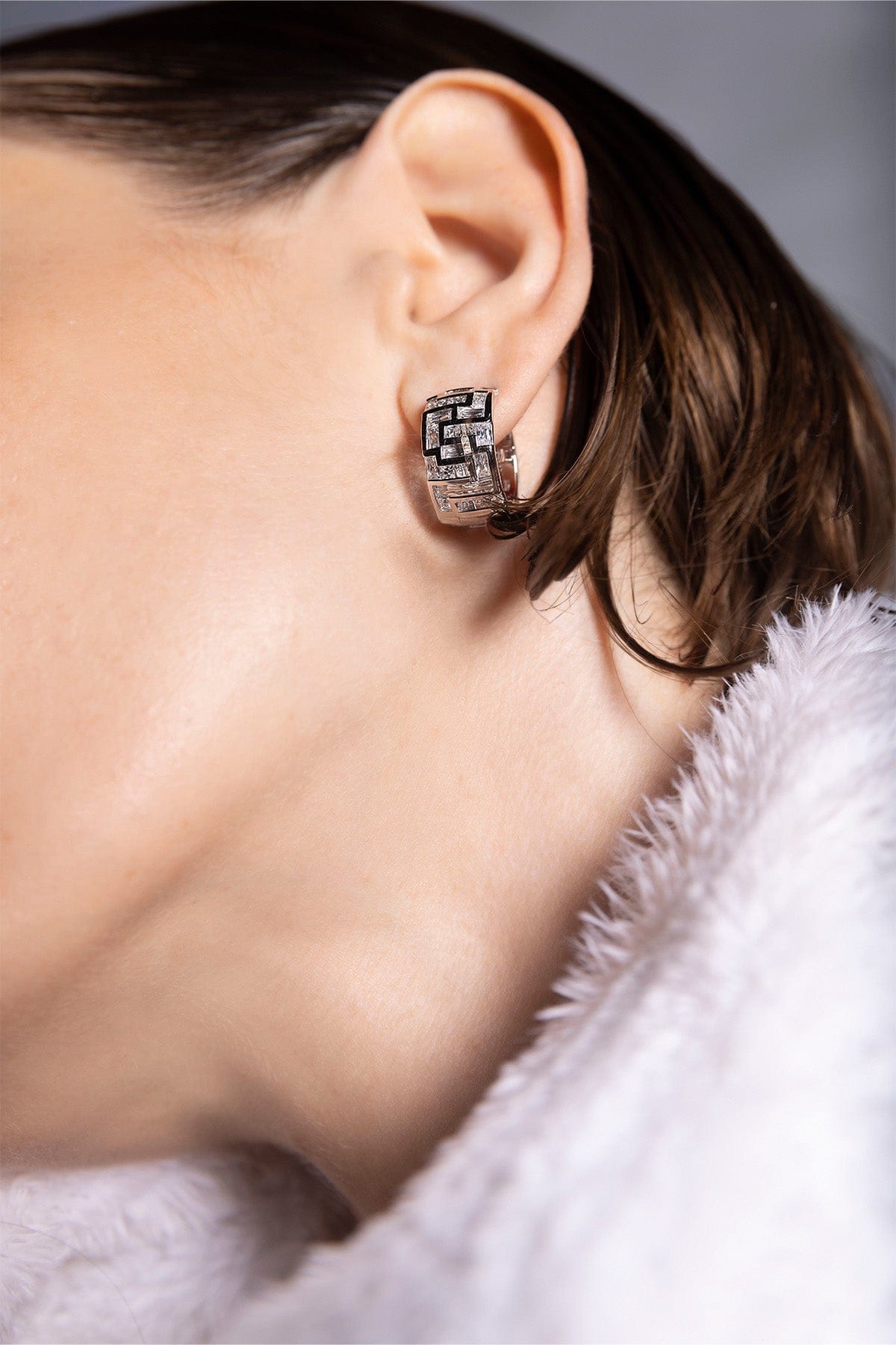 Close-up of a labyrinth earring from APM MONACO worn by a person with a blurred background