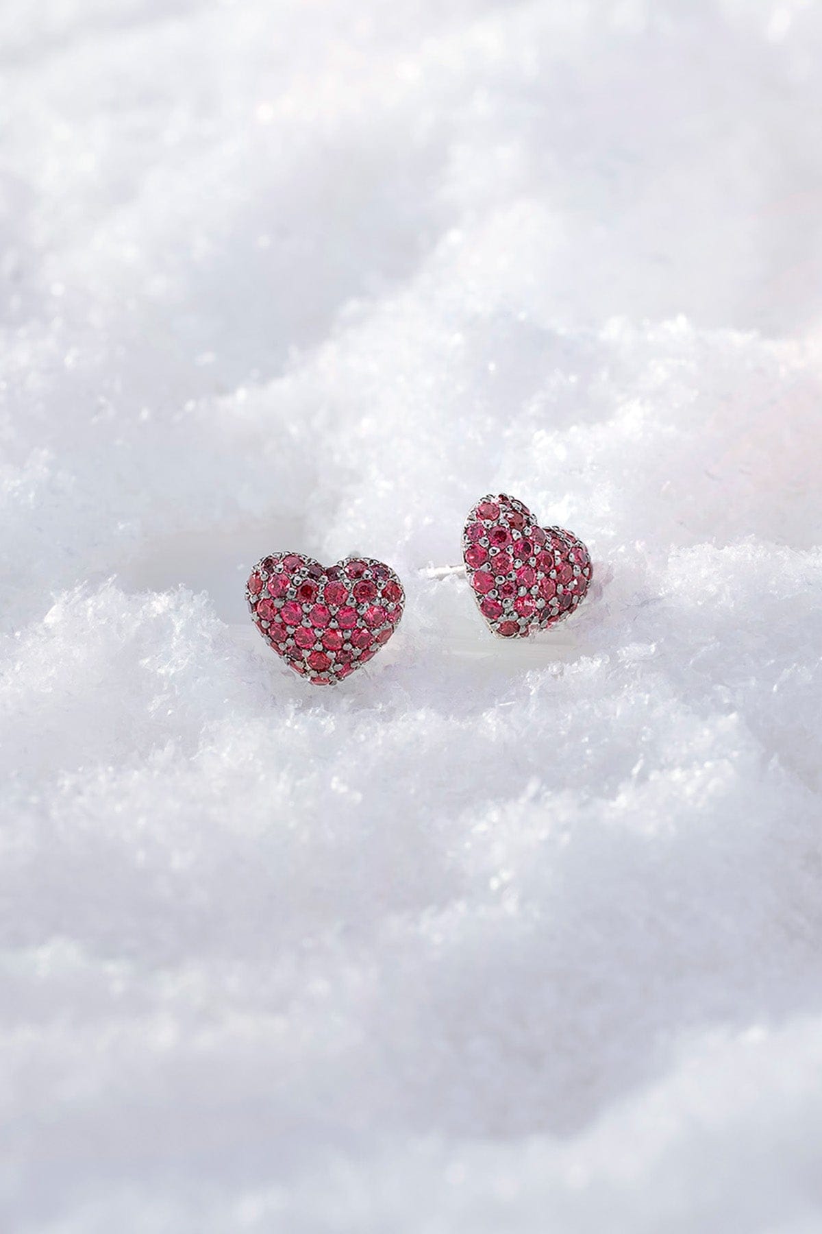 APM MONACO heart-shaped earrings with fuchsia stones on a white snowy background