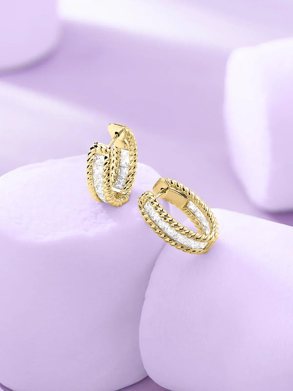 APM Monaco Yellow Gold Torsade design earrings on marshmellow purple background